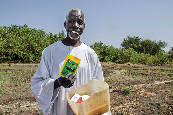 Un agricultor anciano en Sudán del Sur sostiene semillas distribuidas por la FAO. © FAO/Lieke Visser